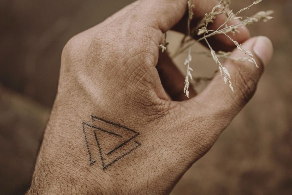 Pequeño triángulo como tatuaje minimalista en el dorso de una mano