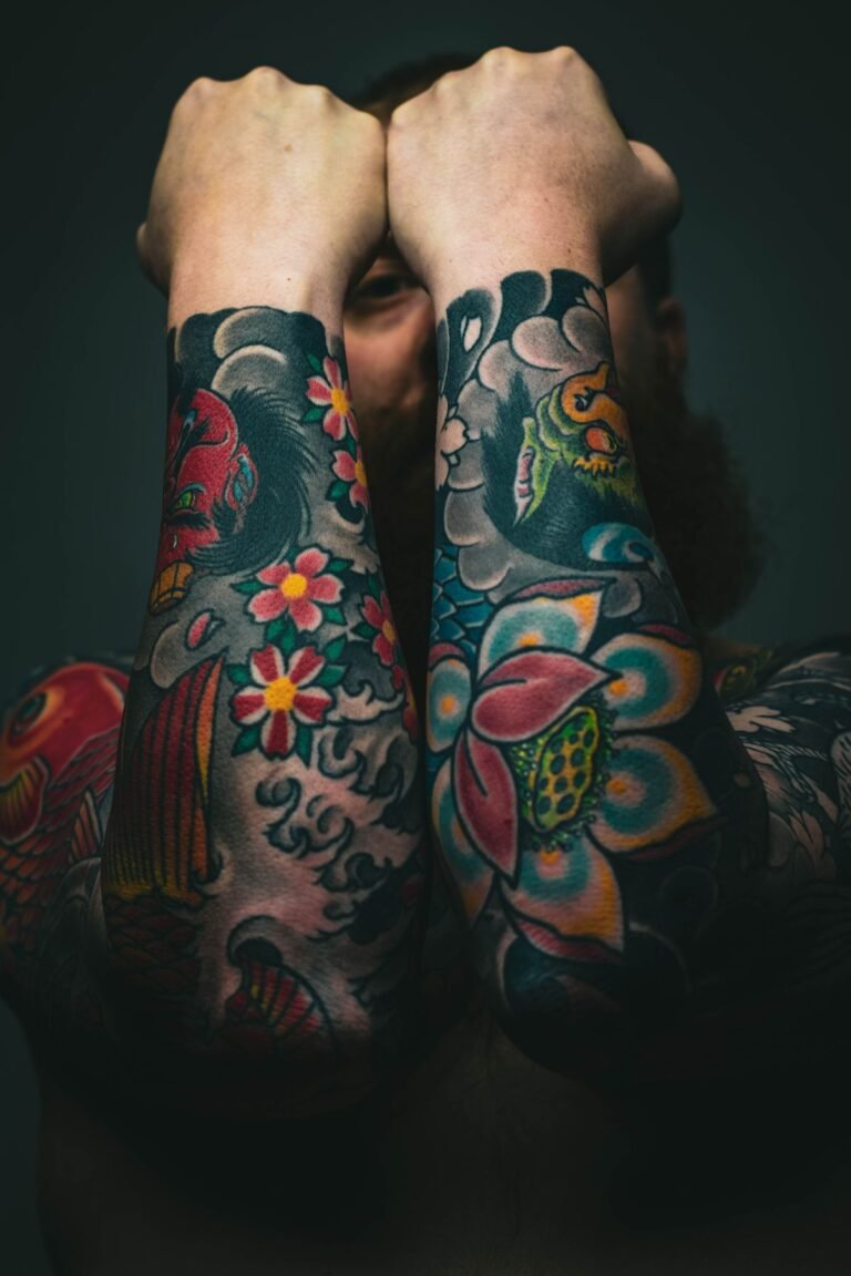 Dos antebrazos cubiertos de tatuajes old school de colores con flores y carpas koi